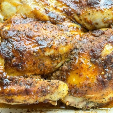 Close-up of Southern baked spatchcock chicken with golden skin, drizzled with hot honey glaze and pan juices.