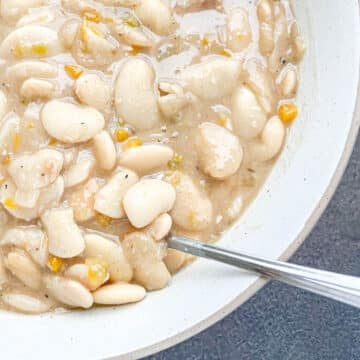 Close-up of creamy Southern lima beans (butter beans) in a white bowl with a spoon.