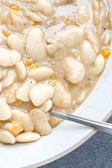 Close-up of creamy Southern lima beans (butter beans) in a white bowl with a spoon.