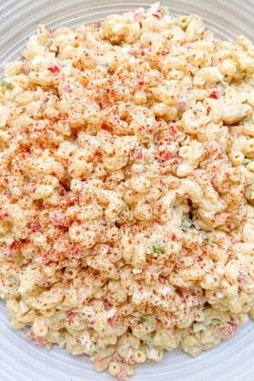 Southern macaroni salad garnished with smoked paprika and arranged on a white serving platter.